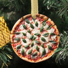 a homemade pizza ornament hanging from a christmas tree with green leaves on it