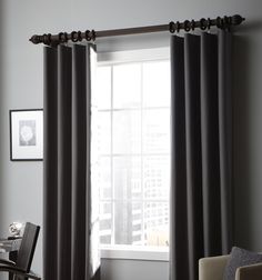 a living room filled with furniture and a window covered in gray drapes next to a chair