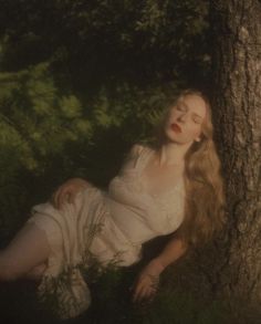 a woman laying on the ground next to a tree