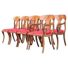 a set of six chairs with red cushions and wooden frames, all in the same design