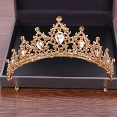 a gold tiara sitting on top of a wooden table next to a black box