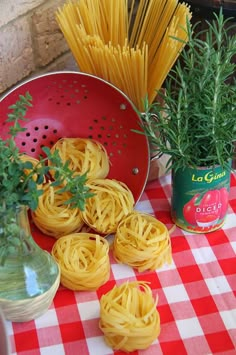 some pasta and herbs on a red checkered table cloth next to a cola can