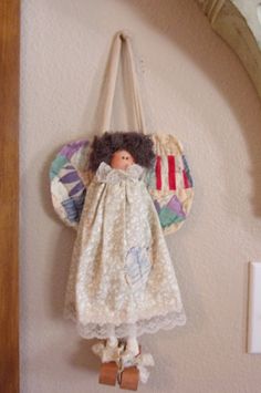 a doll hanging from the side of a wall with a purse on it's back