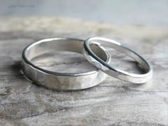 two silver rings sitting on top of a piece of wood