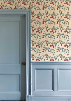 an open door in front of a wallpapered wall with cherries on it