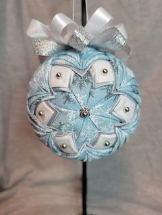 a blue and white ornament hanging from a metal pole with a bow on it