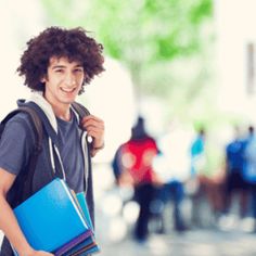 a young man with curly hair is holding a blue folder and smiling at the camera