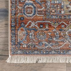 an orange and blue area rug with fringes on the bottom, sitting on a wooden floor