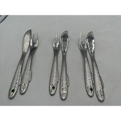 four pieces of silverware with green stones on them