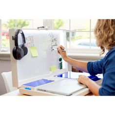 a woman writing on a white board with headphones and ear phones next to her