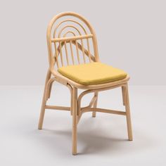 a wooden chair with a yellow cushion on the seat and backrest, in front of a gray background