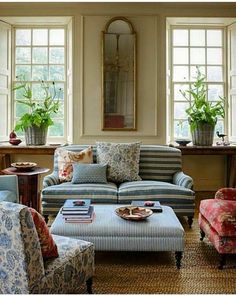 a living room filled with lots of furniture next to two windows and a coffee table