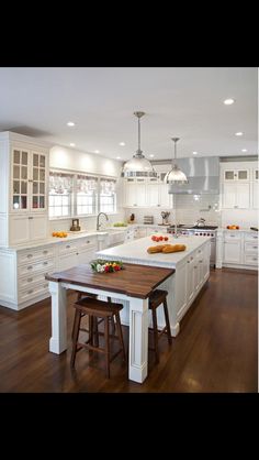 a large kitchen with white cabinets and wooden floors