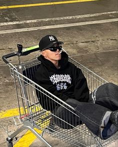 a man sitting in a shopping cart with a baseball cap on