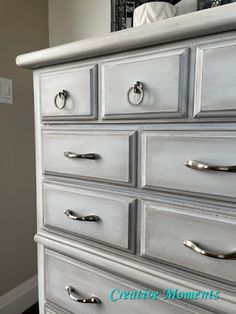 a white dresser with silver handles in a room