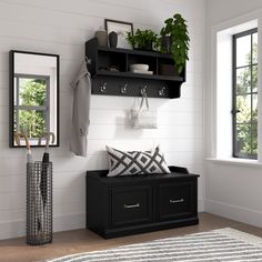 a black bench sitting under a window next to a wall mounted coat rack and mirror