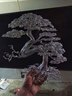 a person holding up a glass bonsai tree