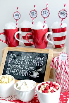 red and white candy canes are in cups with marshmallows on the table