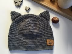 a gray knitted hat with ears on top of a table next to nuts and leaves