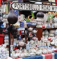 an outdoor market with many different kinds of teapots and cups on display for sale