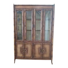 an antique china cabinet with glass doors and bamboo panels on the front, against a white background