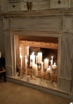 a fireplace with candles lit in front of it and a mirror on the wall behind it