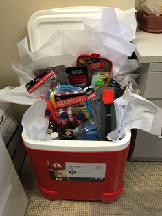 a red and white cooler filled with lots of different types of items on top of a carpeted floor