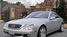 a silver mercedes cls parked on the street in front of a gated house