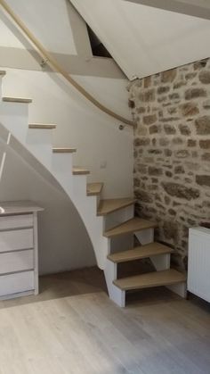 an empty room with stone walls and wooden steps leading up to the second floor area