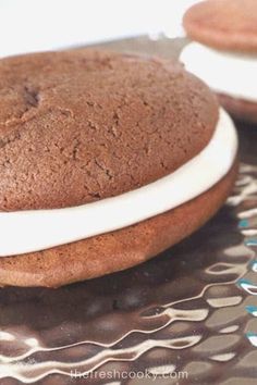 two cookies with white frosting are sitting on a glass tablecloth next to each other