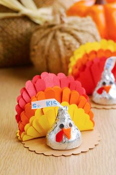 three turkeys are sitting on a table next to pumpkins