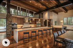 an open kitchen and dining room with wood flooring, large windows, and bar stools