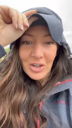 a woman with long hair wearing a gray jacket and hat is posing for the camera