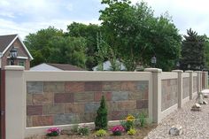 a stone fence with flowers in the foreground