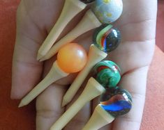 a person is holding five different colored marbles