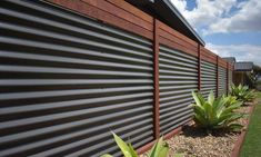 the side of a building with some plants growing on it's sides and grass in front