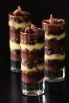 three glasses filled with desserts sitting on top of a black table next to each other