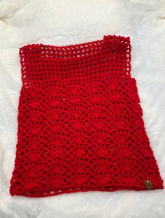 a red crocheted blanket laying on top of a bed