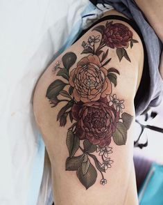 a woman's arm with flowers on it and leaves around the arm, in front of her