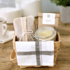 a wooden table topped with a basket filled with tea bags and towels next to a cup