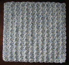 a crocheted dishcloth is sitting on a wooden table with a brown surface