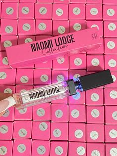 the lip glosses are on display in front of pink boxes