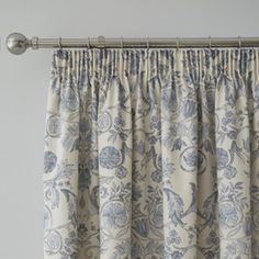 a curtain with blue and white floral print on the top, hanging from a metal rod