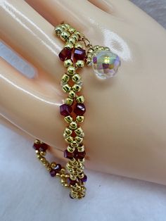 "This elegant and dainty bracelet is hand woven using 6lb Crystal Fireline, 4mm Garnet AB Helix Crystals, 8/0 Toho Seed Beads in Permanent Finish Galvanized Starlight (gold tone), gold stainless steel lobster claw clasp, 2\" gold stainless steel extender/adjustable chain, and an 8mm crystal drop charm. Great as a gift for you or to give to someone special.  Wear it to formal events such as weddings, proms, banquets, or special occasions like family get togethers, or simply enjoy wearing it every Seed Bead Bracelet, Dainty Bracelet, Dainty Bracelets, Personalized Bracelets, Seed Bead Bracelets, Crystal Drop, Braided Bracelets, Bead Bracelet, Seed Bead