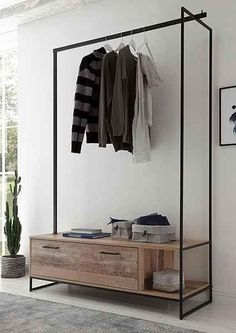 a clothes rack in the corner of a room next to a dresser and potted plant