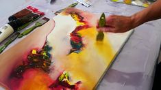 a person is painting on a canvas with paintbrushes