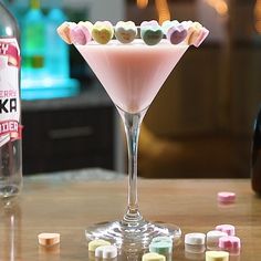 a pink martini with candy hearts in it and a bottle of booze next to it