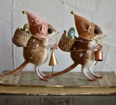 two little mice with bells and hats on their heads are standing next to each other