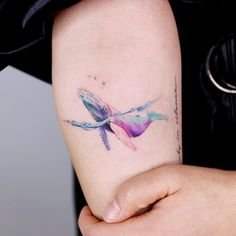 a woman's arm with a colorful bird tattoo on the left side of her arm