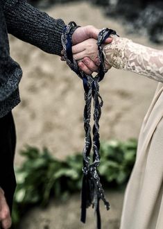 two people are holding hands with chains attached to their wrists and wearing lace on them